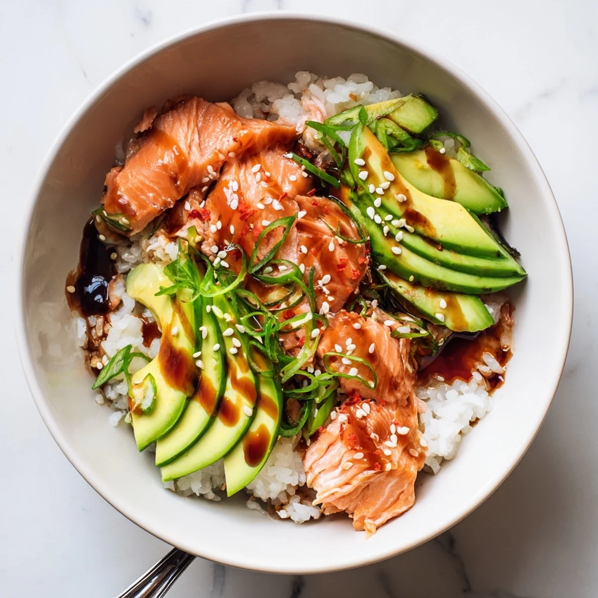 Flaky leftover salmon and rice bowl topped with fresh avocado and cucumber.