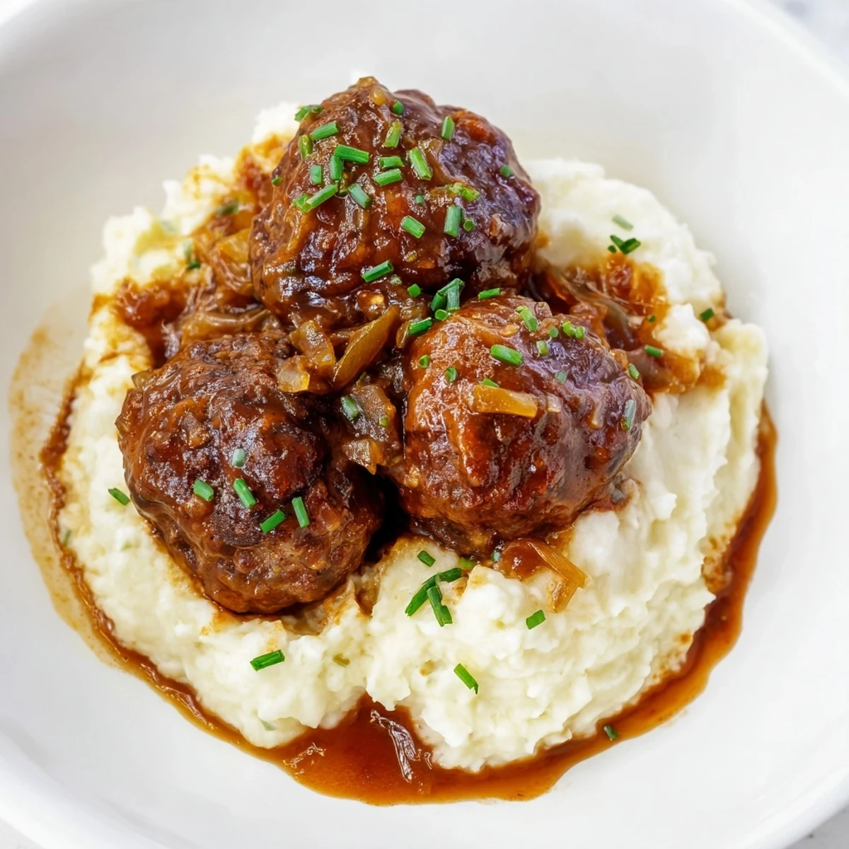 BBQ Meatballs & Mashed Potatoes: Tender, saucy meatballs resting atop fluffy, creamy mashed potatoes with fresh herbs.