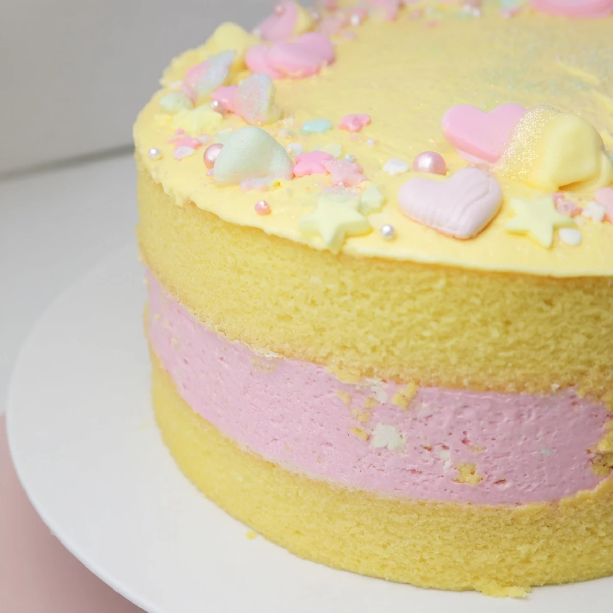 Frosted in soft yellow, the Château de Princesse Cœurs et Étoiles cake features pink buttercream between layers.