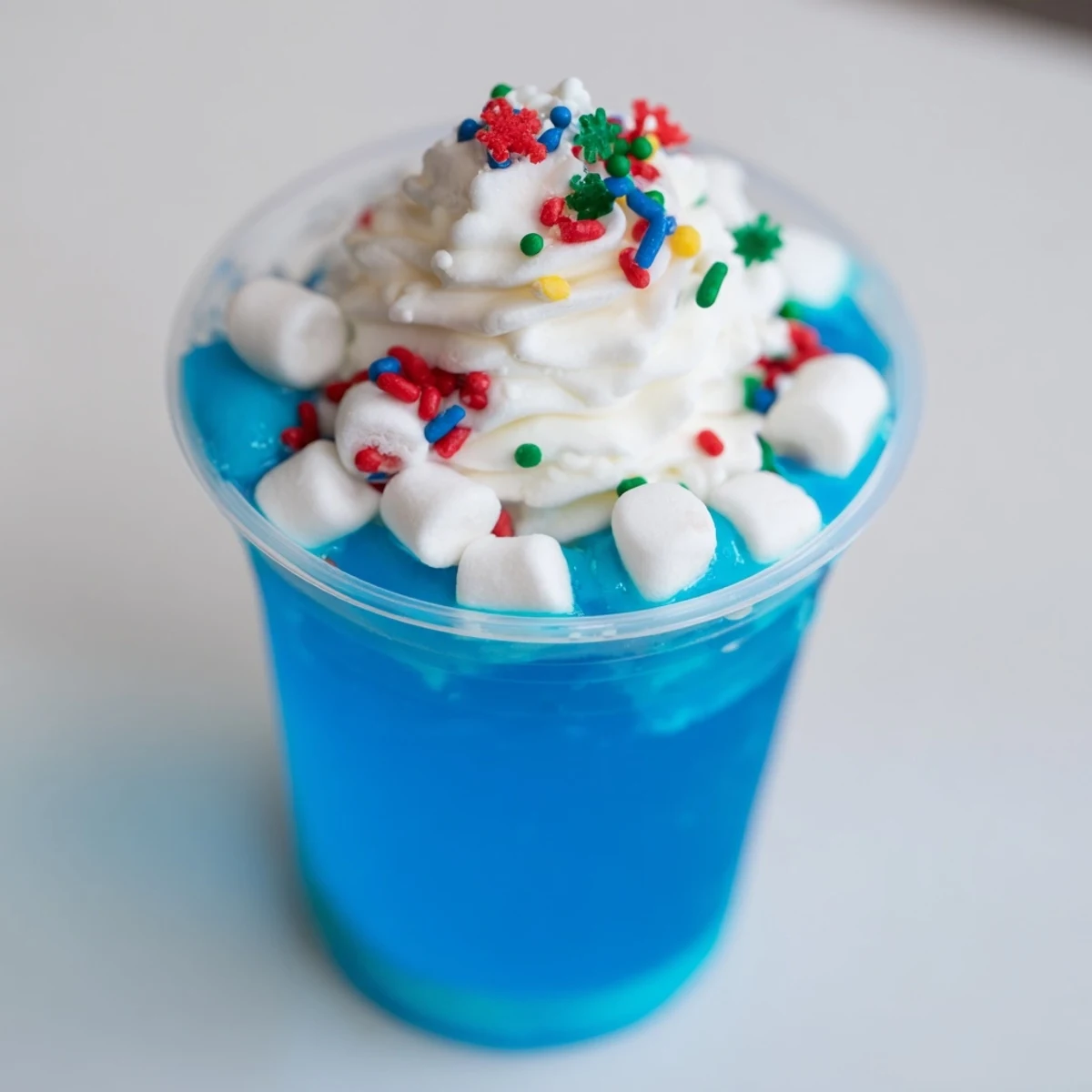 Layered snow globe Jello cups, a delightful dessert with jiggling blue gelatin, perfect for holidays.