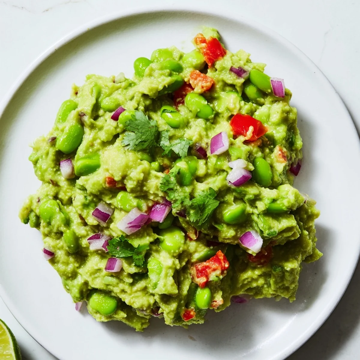 Creamy edamame guacamole, a vibrant green dip with visible chunks, ready to be served with chips.