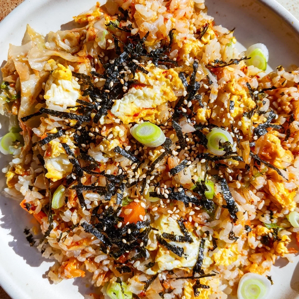 Steaming bowl of Spicy Kimchi Fried Rice, garnished with sesame seeds and green onions, ready to enjoy.