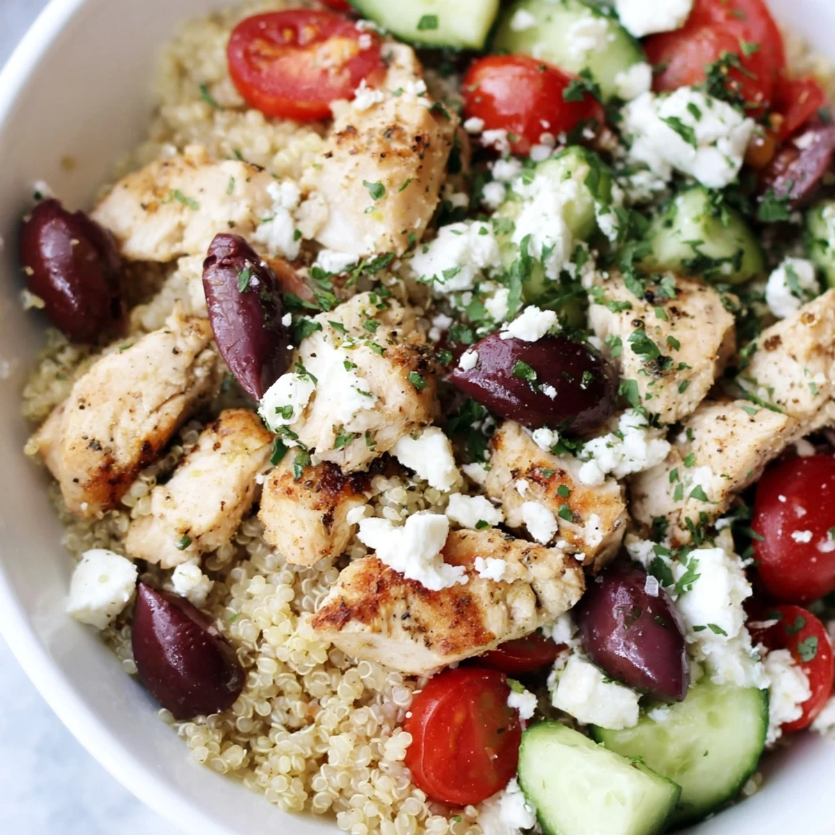 Freshly cooked Mediterranean Chicken Bowl showcases golden chicken pieces, fluffy quinoa, and vibrant cherry tomatoes on a rustic plate.