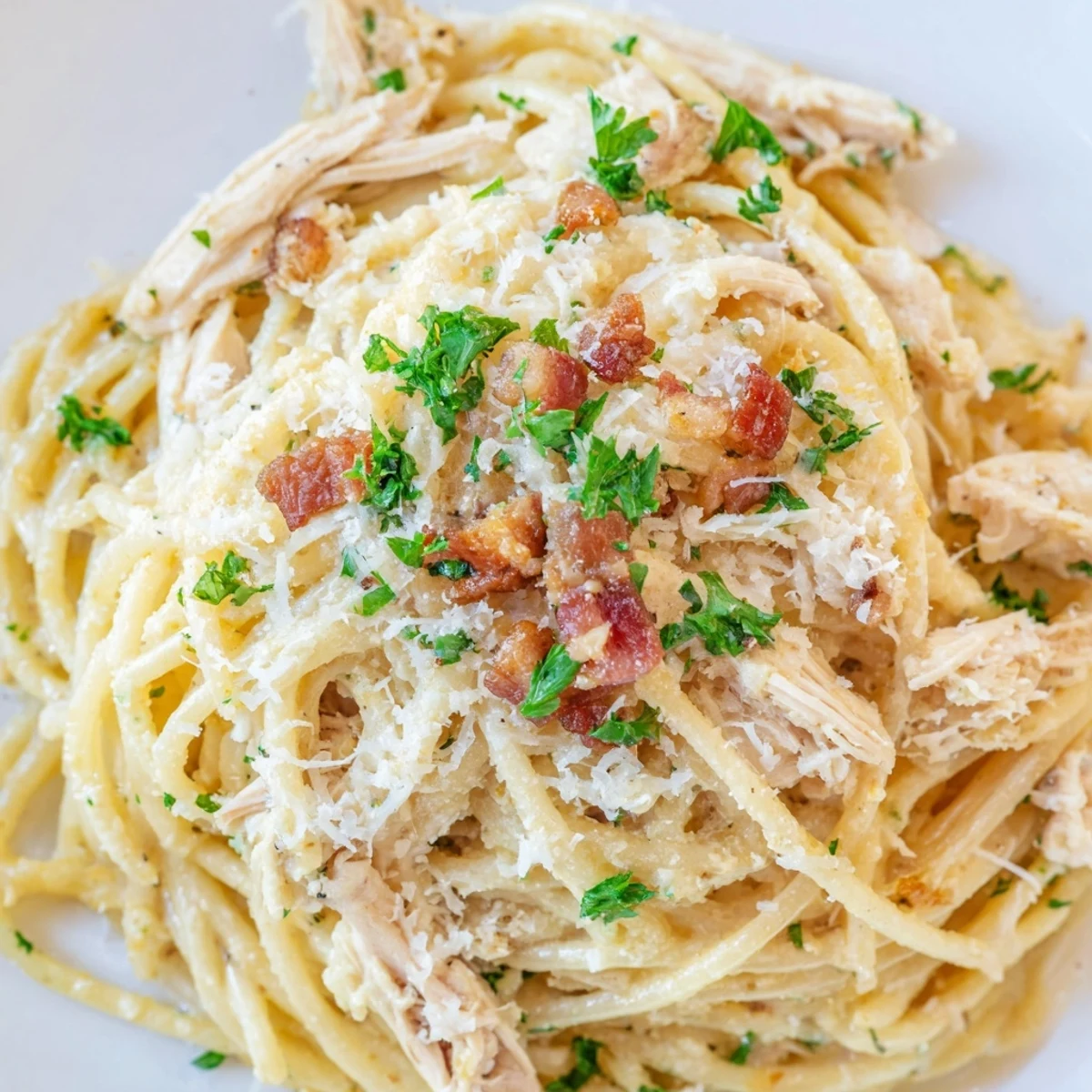 Golden, glossy strands of Chicken Carbonara in a skillet, showcasing the rich egg-Parmesan sauce coating spaghetti and savory shredded chicken.