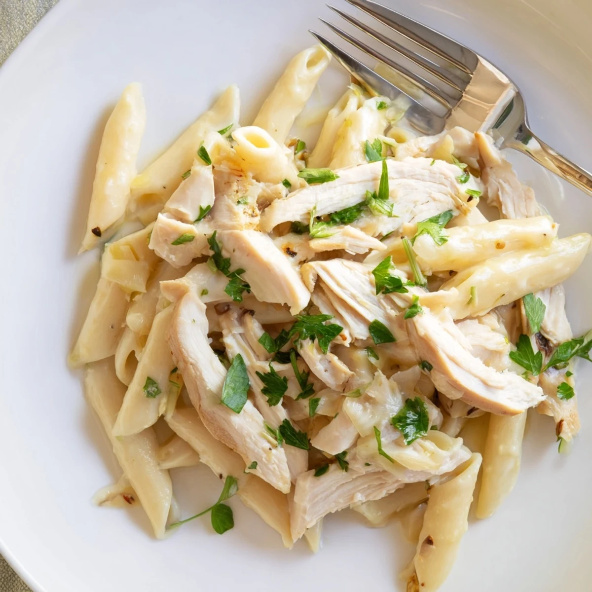 A close-up of creamy Roasted Garlic Chicken Penne, with tender chicken pieces and a silky, golden sauce coating each noodle.