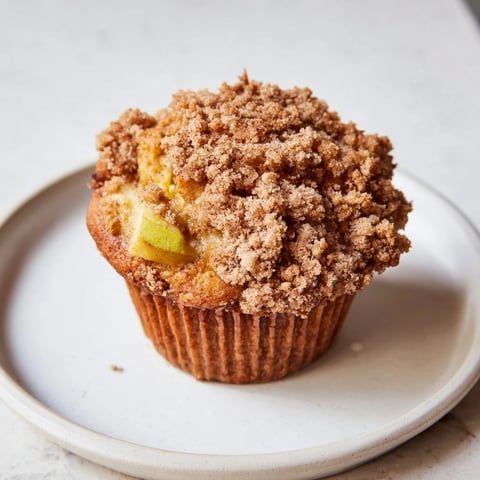Golden-topped apple muffins with crumb topping, perfect snack for a cozy morning or as dessert.