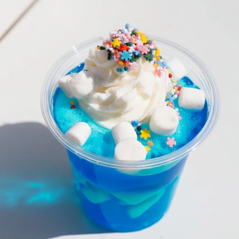 Vibrant snow globe Jello cups, shimmering with blue gelatin, marshmallows, and festive sprinkles.