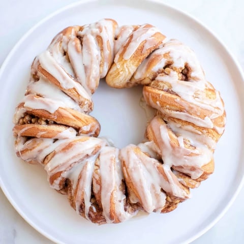 Soft, warm cinnamon roll pull-apart wreath, glazed and ready for sharing at a holiday brunch.