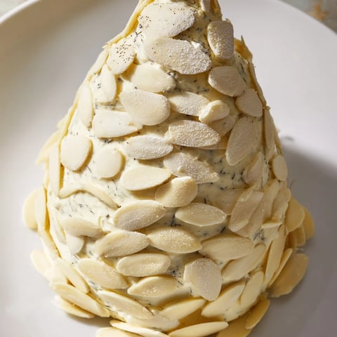 Snowy Pinecone Centerpiece displays a festive, cheese-based appetizer with almond "scales" and sugared garnish.