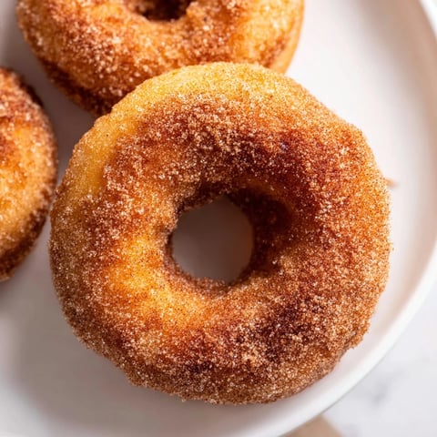 Golden 1-Minute Air Fryer Donuts, coated in cinnamon sugar, perfect for a quick and sweet dessert.