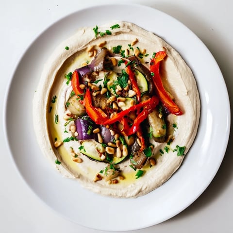 Hummus Roasted Veggies: vibrantly colorful, roasted vegetables sit atop creamy, smooth hummus, ready to serve.