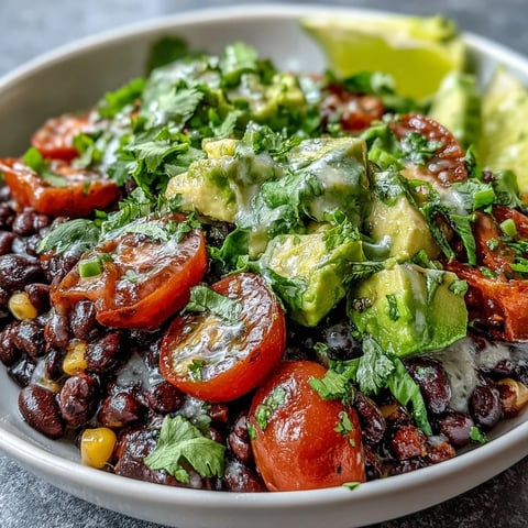 Freshly prepared Black Bean and Veggie Bowl with diced avocado, cherry tomatoes, and a zesty lime dressing ready to eat.