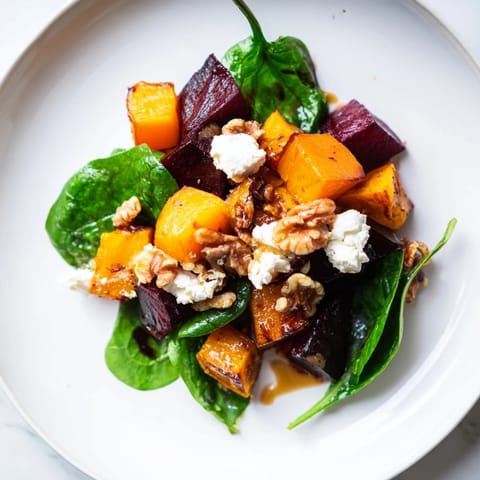 Vibrant image shows the Roasted Beet, Butternut & Spinach Salad, ready to be enjoyed with creamy goat cheese.