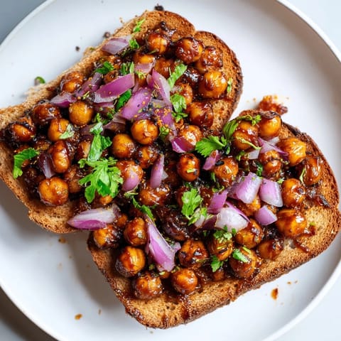 Close-up of bubbling BBQ chickpeas on toast, garnished with fresh cilantro, a delicious vegan meal.