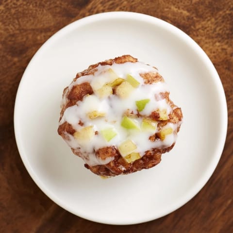 Freshly fried apple fritters, aromatic with cinnamon and nutmeg, served warm with a sweet glaze drizzle.