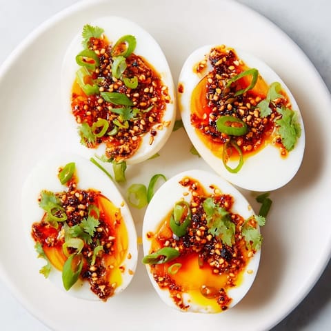 A close-up shot of perfectly cooked chili oil eggs, drizzled with a spicy, vibrant sauce.