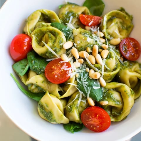 Creamy cheese tortellini tossed with basil pesto, juicy tomatoes, and spinach, served chilled with a squeeze of fresh lemon.