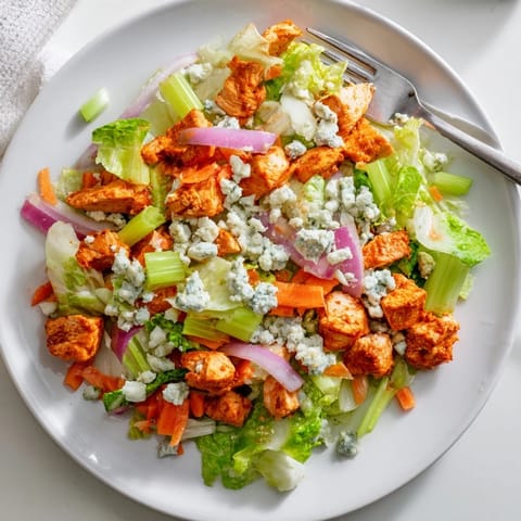 Blue cheese crumbles and diced celery top the Buffalo Chicken Chopped Salad, served with ranch dressing on the side.