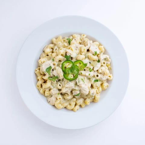 Green Chili Chicken Mac is served hot from the pan, garnished with fresh cilantro and optional spicy jalapeño slices for color.