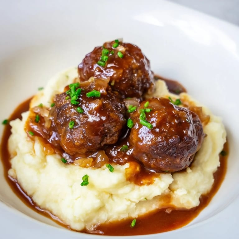 Golden-glazed BBQ Meatballs smothering the mashed potatoes present a delicious, well-balanced meal.