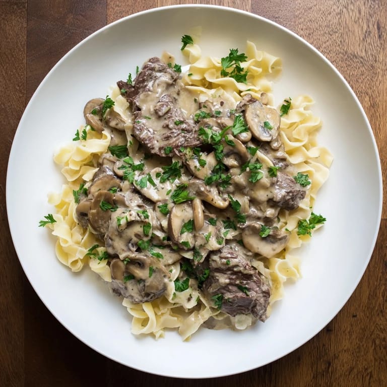 Picture this: a generous serving of Creamy Mushroom Beef Stroganoff, garnished with parsley, on a white plate.