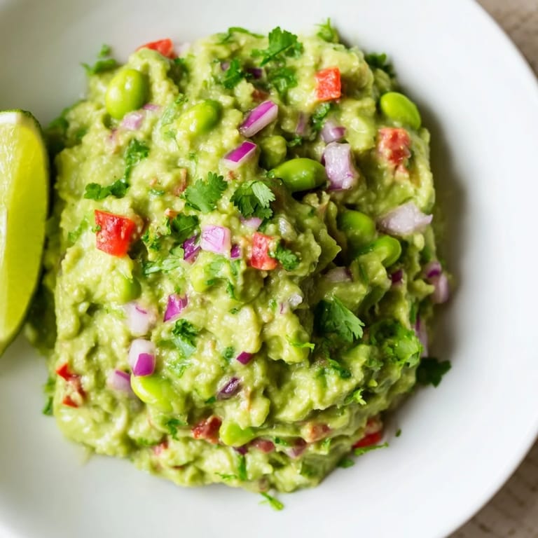 Freshly made edamame guacamole, with bits of red onion and cilantro, a flavorful appetizer.