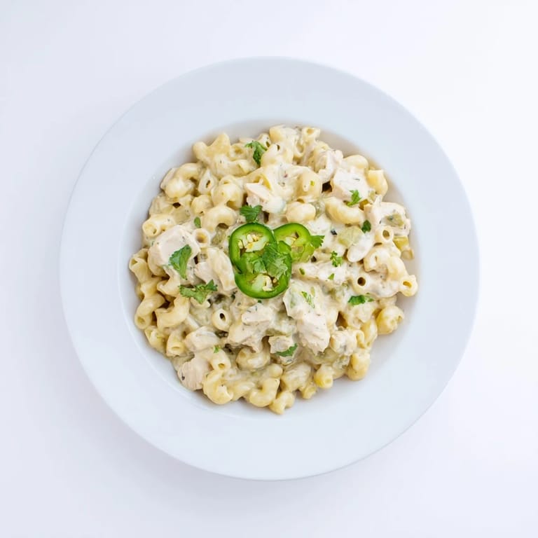 Green Chili Chicken Mac is served hot from the pan, garnished with fresh cilantro and optional spicy jalapeño slices for color.