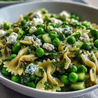 Fresh spring peas and mint in Fresh Spring Pea and Mint Pasta Salad with Lemon Vinaigrette served chilled on a white plate.