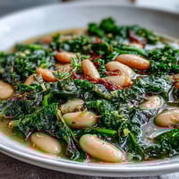 Hearty kale and white bean soup with lemon and garlic, steaming in a rustic bowl, garnished with fresh parsley.  
