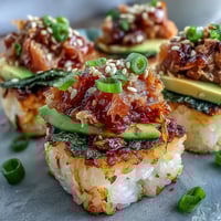 Crispy golden rice squares topped with spicy tuna and creamy avocado slices for a perfect sushi appetizer.  